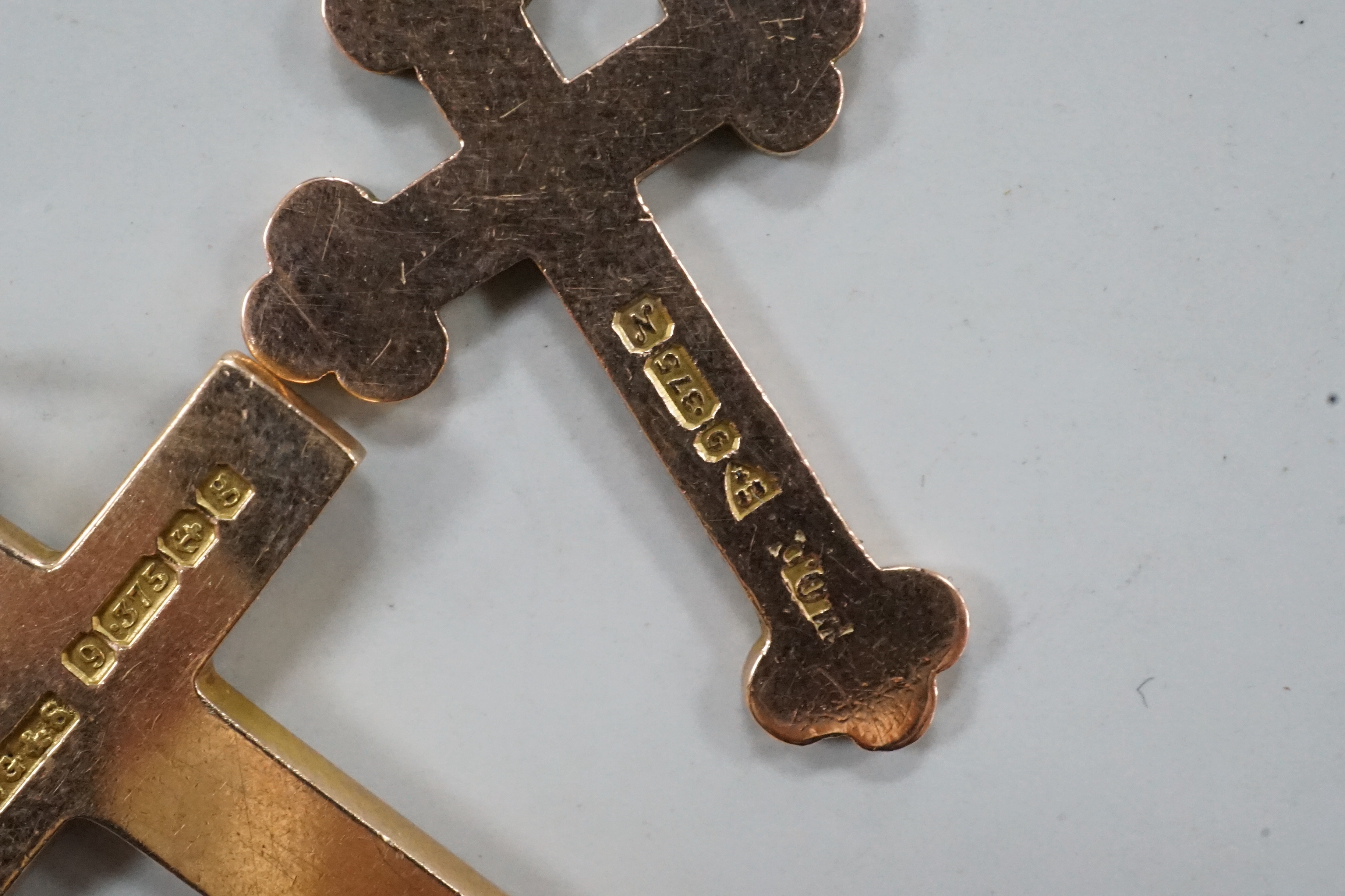 Two early 20th century 9ct gold cross pendants, three other 9ct charms including articulated fish, gross weight 11.8 grams.